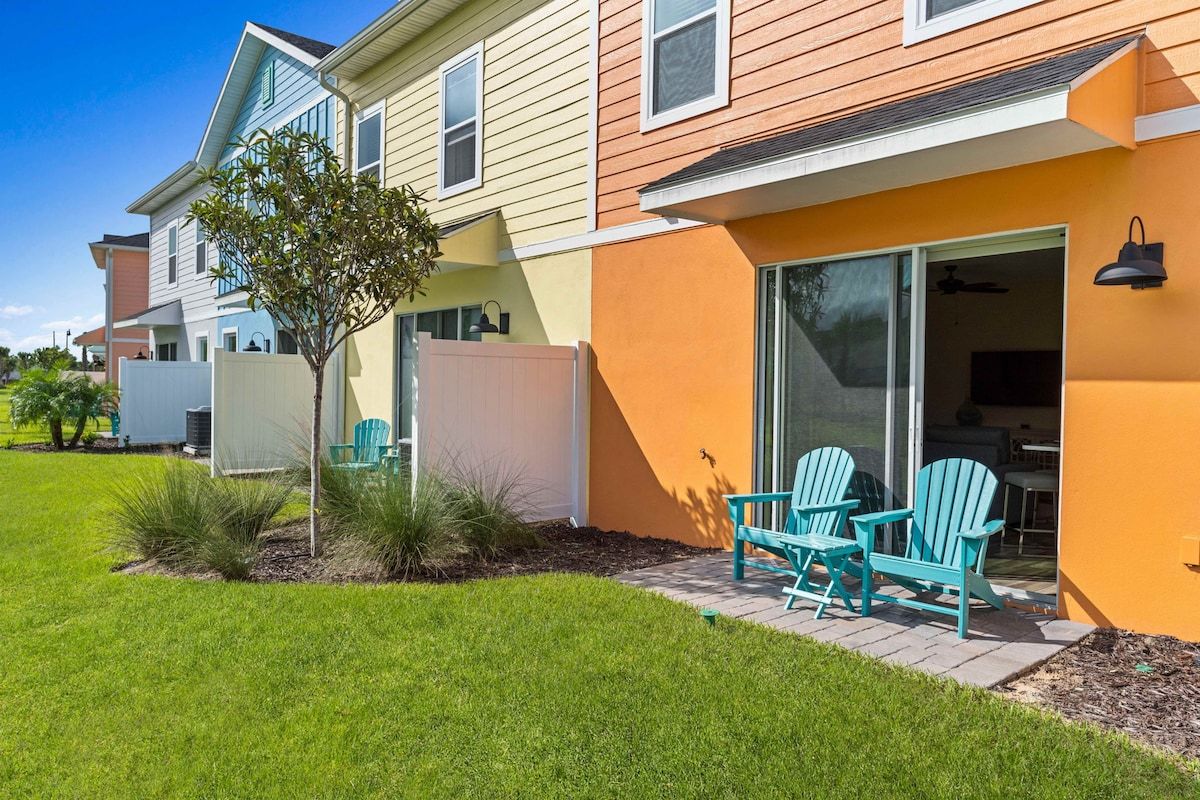 A residential building with a patio area, outdoor seating, and a sliding glass door entrance.