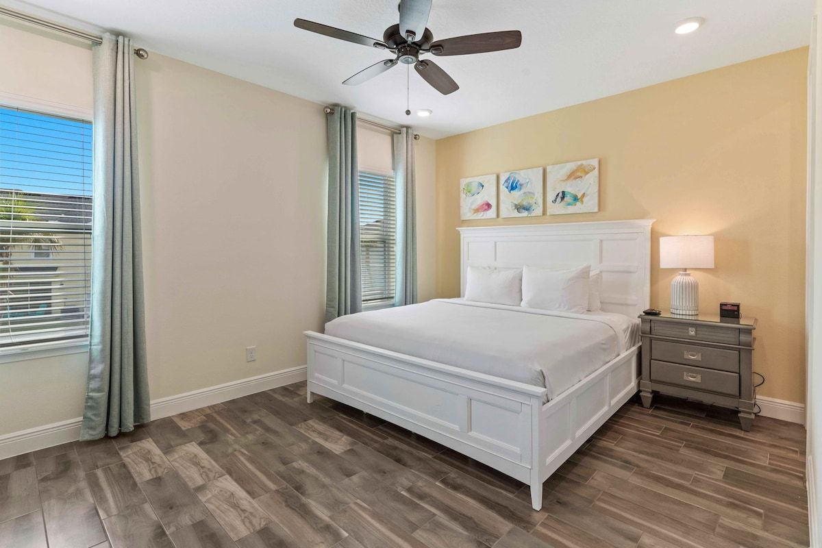 - Serene bedroom with a plush bed, calming tones, and coastal artwork
- Sunshine by day, blackout curtains by night, ideal for both early birds and sleepyheads
- Ceiling fan, warm lighting, and natural wood floors add just the right touch of comfort