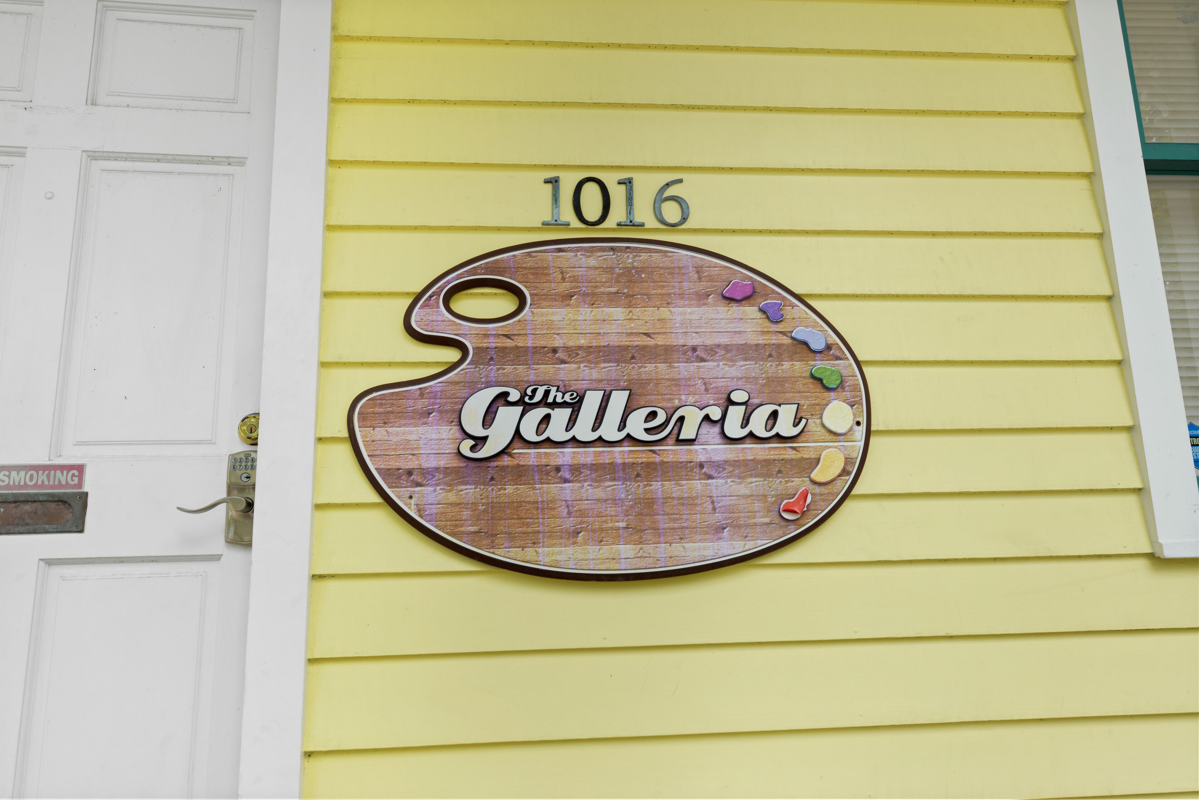 Un edificio giallo con un cartello che riporta "The Galleria" e il numero "1016" sopra.