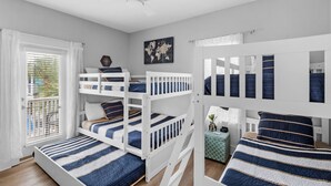 A multi-level bunk bed room with white railings, a ceiling fan, and a world map on the wall. - Renovated 30A Bungalow 5 Min Walk to Beach!! (Santa Rosa Beach)