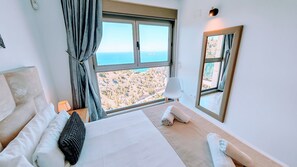 A hotel room with a large bed, a view of the landscape, a window, and a mirror. - Benidorm sky - High-rise apartments (Benidorm)