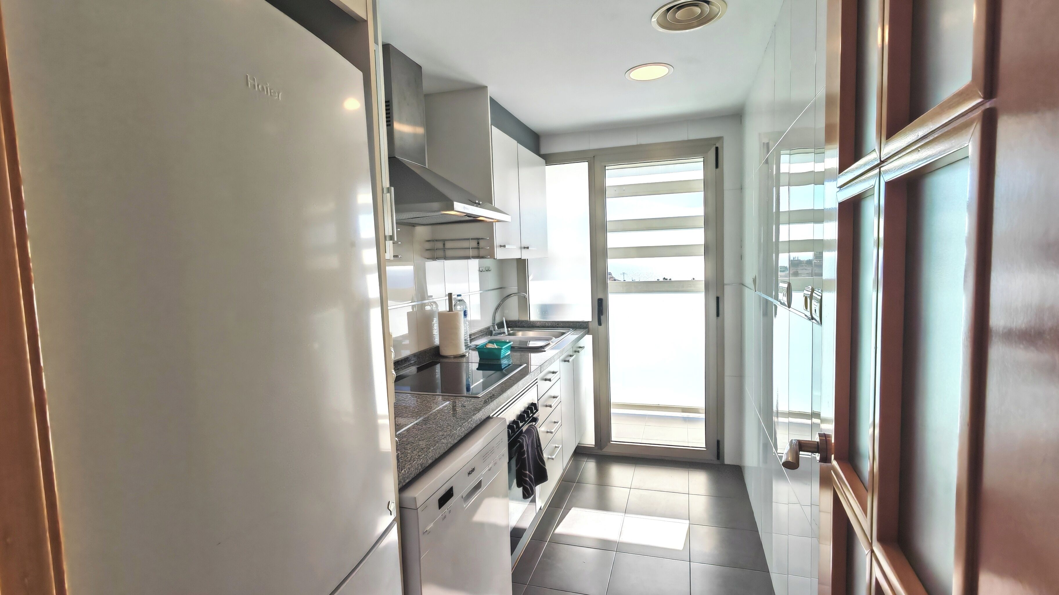 Uma cozinha moderna com máquina de lavar louça embutida, pia e janela com vista para o exterior.