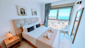 A hotel room with a bed, a nightstand, a lamp, a chair, and a large window with a view. - Benidorm sky - High-rise apartments (Benidorm)