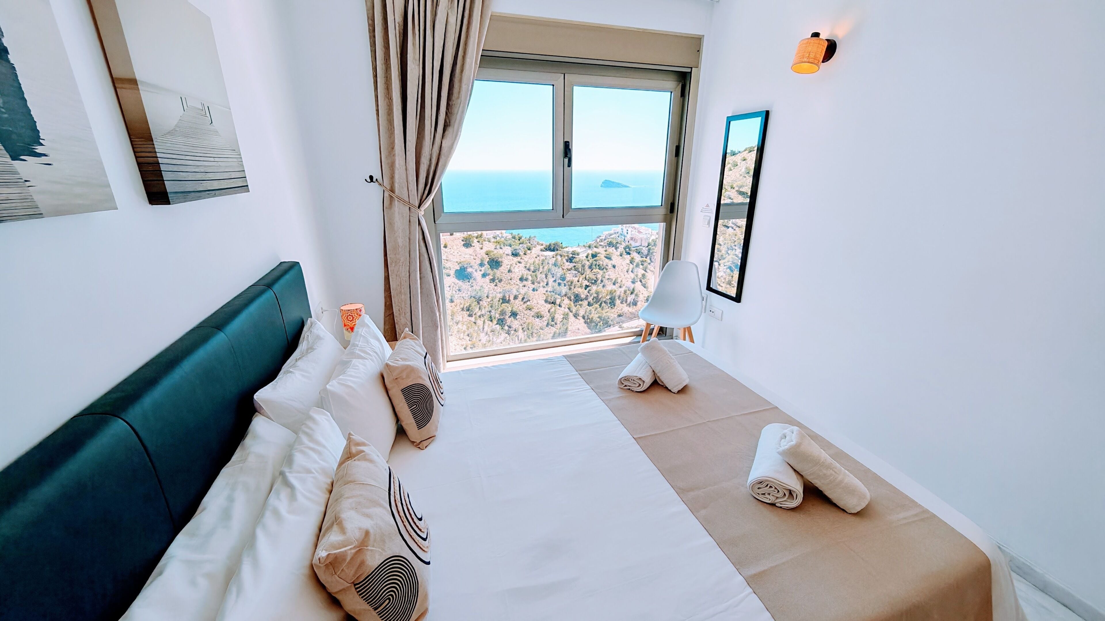 Une chambre d’hôtel avec un lit, une vue sur la mer et une fenêtre avec des rideaux.