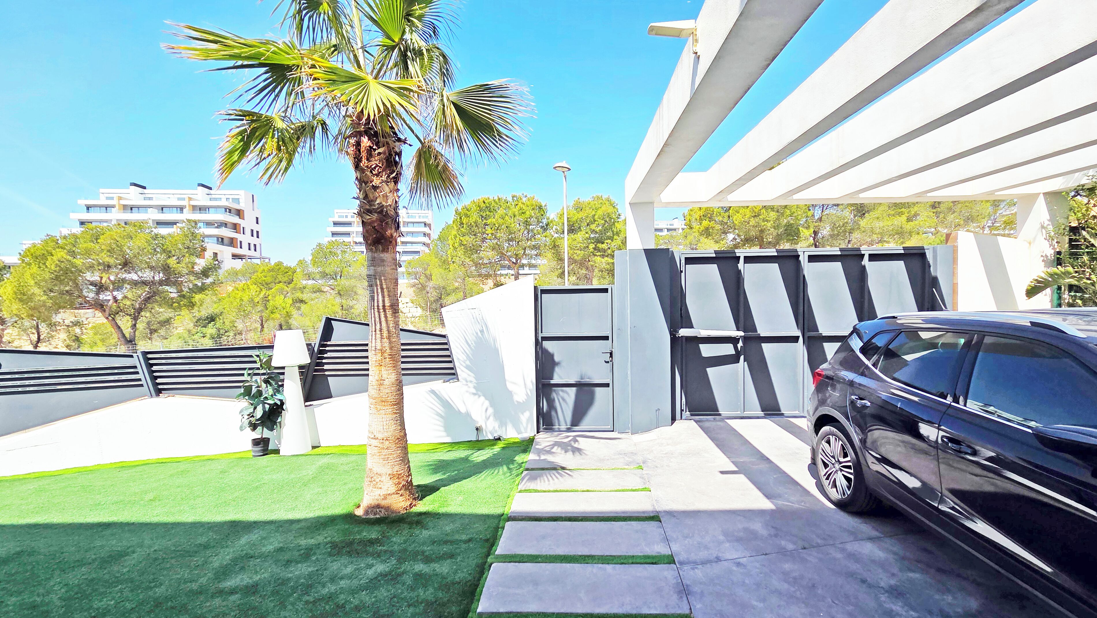 A modern building with a carport, a palm tree, and a clear sky.