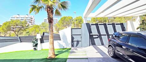 A modern building with a carport, a palm tree, and a clear sky.