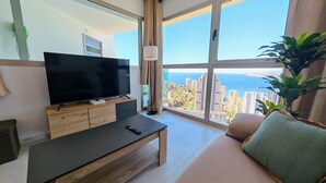 A modern living room with a large TV, a wooden coffee table, a sofa, and a view of the city and sea. - Benidorm sky - High-rise apartments (Benidorm)