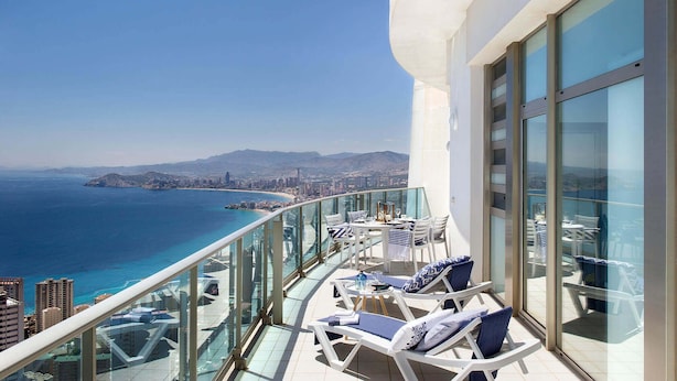 A balcony with a clear view of the sea and cityscape, furnished with lounge chairs and a table. - Benidorm sky - High-rise apartments (Benidorm)