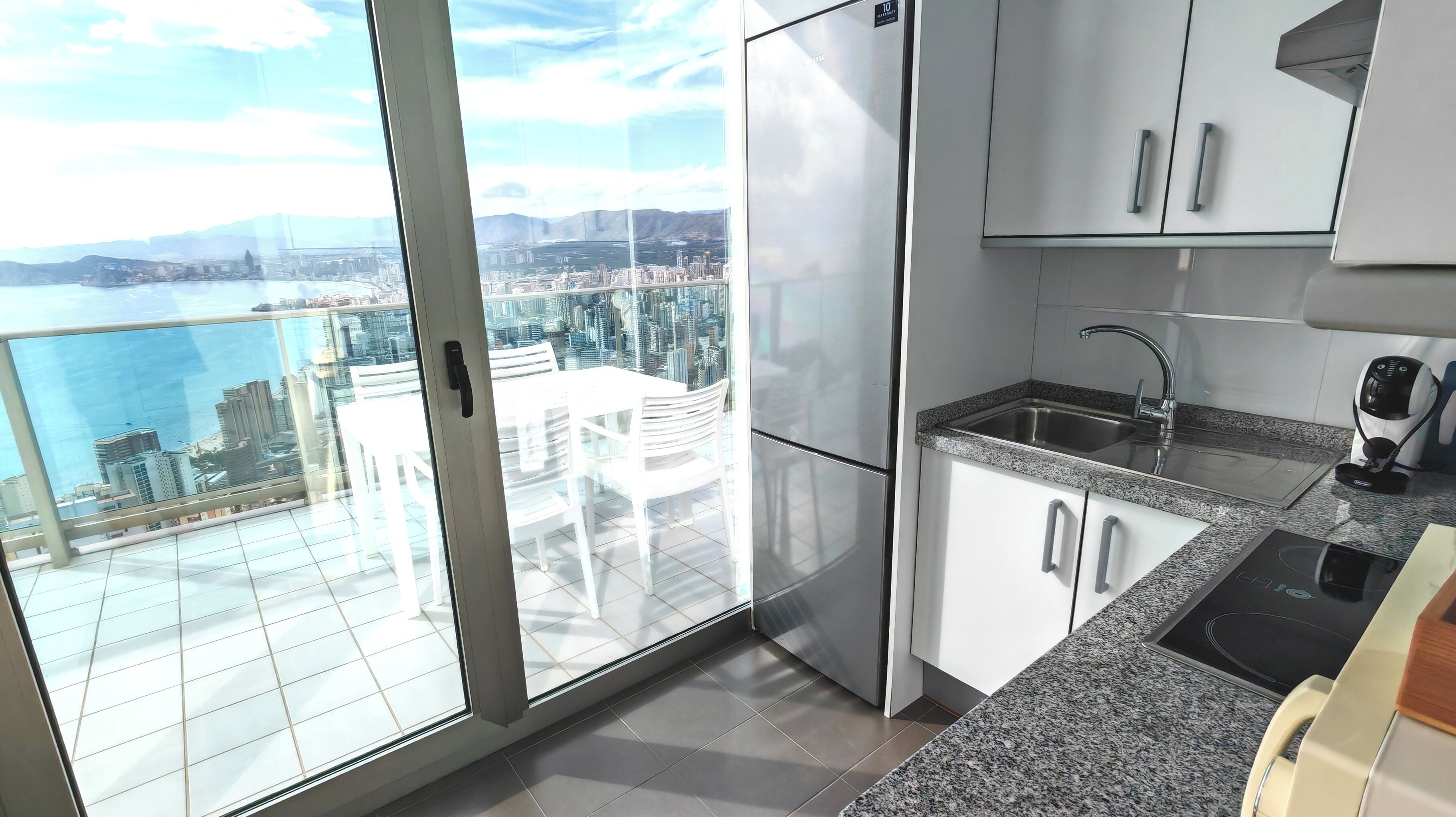 A modern kitchen with a view of a cityscape and a body of water.