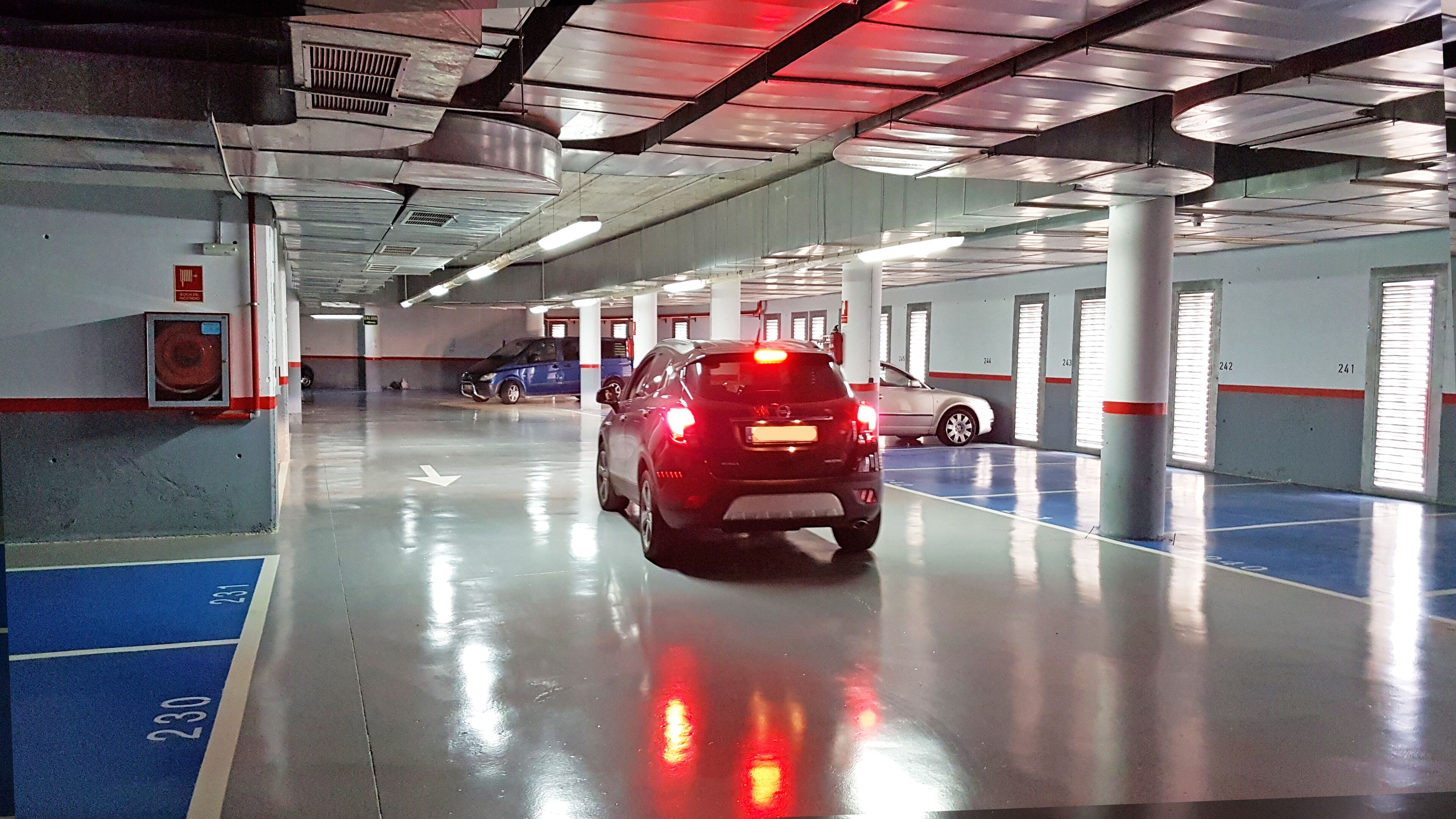 Eine Parkgarage mit in Reih und Glied geparkten Autos, nummerierten Stellplätzen und einem sauberen Boden.