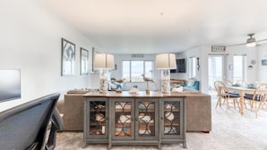 Un salon spacieux avec un grand canapé gris, une table basse en bois agrémentée d’objets décoratifs et un coin repas avec des chaises et une table en bois.