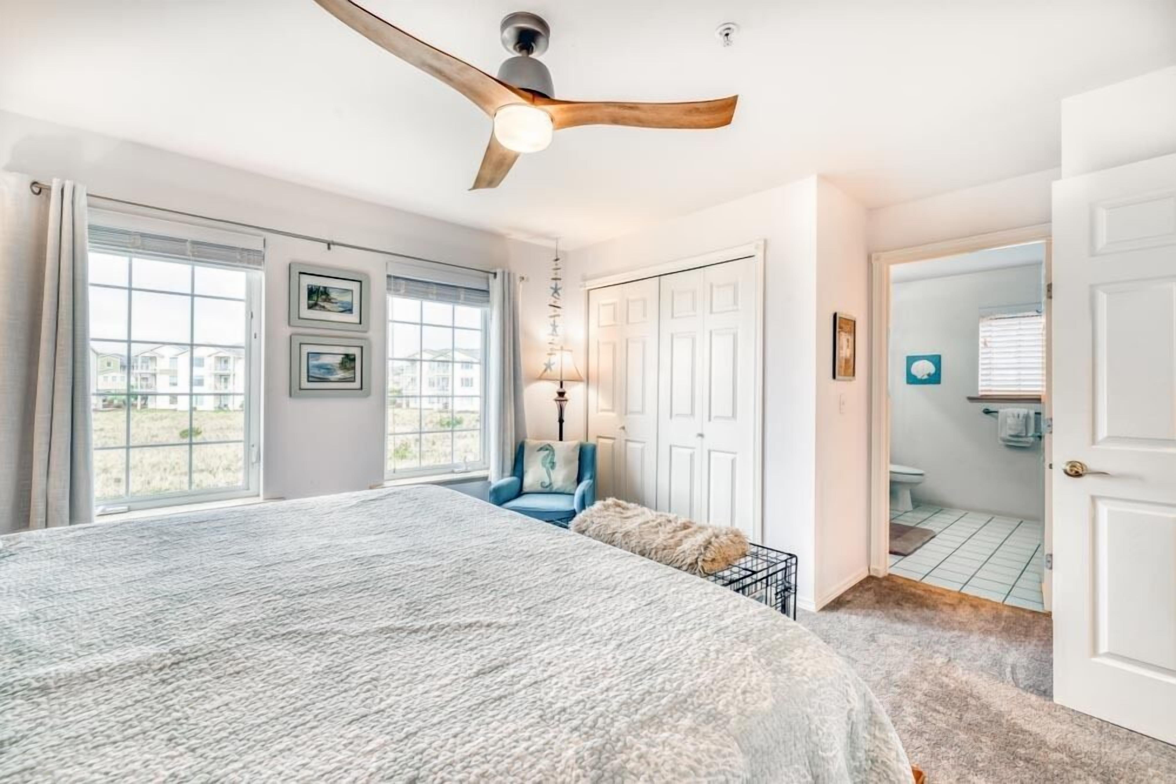 Une chambre avec un grand lit, un ventilateur de plafond et une vue sur l’extérieur.