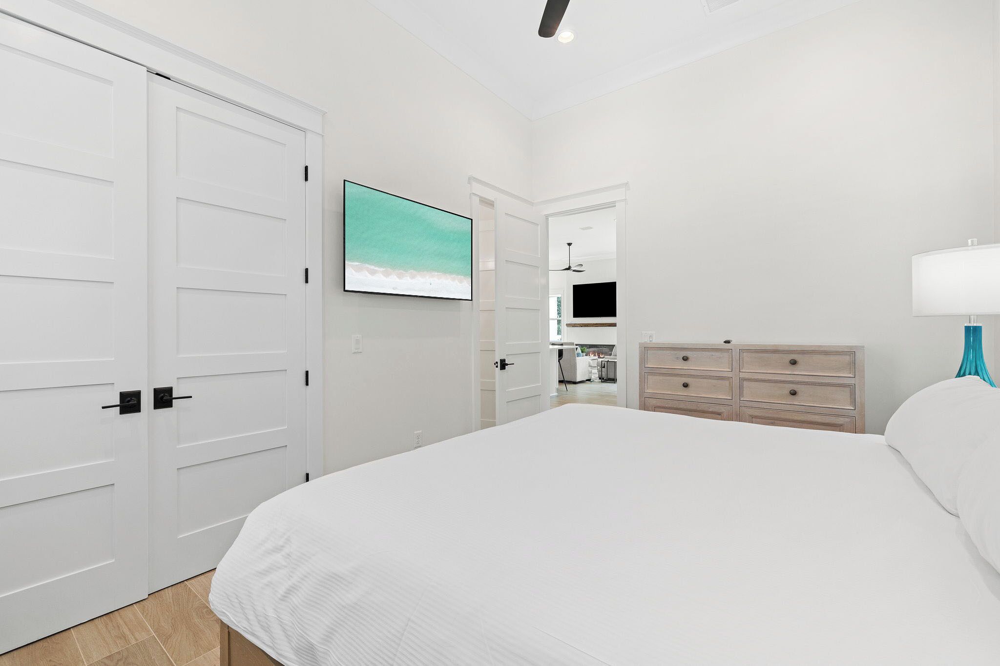Un dormitorio con una cama grande, un televisor montado en la pared, un aparador y una lámpara.