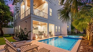 A two-story house with a swimming pool, outdoor seating, and a balcony. - Tailwinds & Tides | Heated Pool | Game Room | Rooftop Deck | Pet Friendly (Santa Rosa Beach)