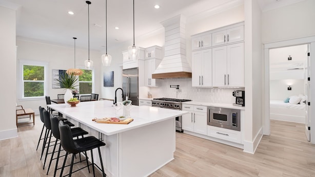 A modern kitchen with white cabinetry, a large island with bar stools, stainless steel appliances, and pendant lighting. - Tailwinds & Tides | Heated Pool | Game Room | Rooftop Deck | Pet Friendly (Santa Rosa Beach)