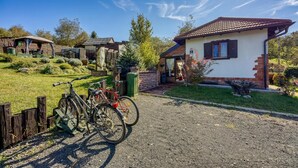 A rural setting with a gravel path leading to a white building with a tiled roof, surrounded by greenery and a bicycle. - Romantic Haven With Hot Tub (Beretinec)