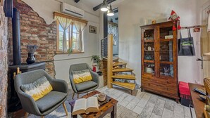 A cozy room with a fireplace, two armchairs, a wooden cabinet, and a staircase. - Romantic Haven With Hot Tub (Beretinec)