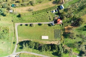An aerial view of a rural property with a large field, a small building with a red roof, and a paved road. - Romantic Haven With Hot Tub (Beretinec)