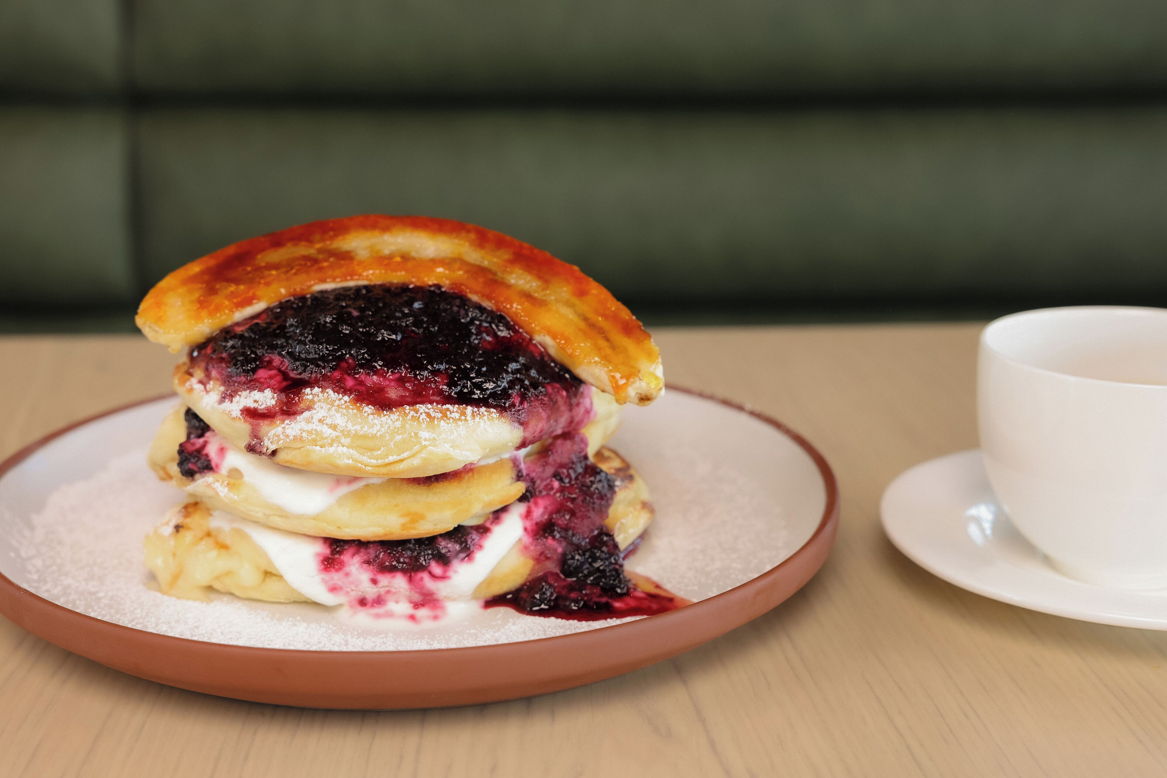 A stack of pancakes with a berry compote on a plate.