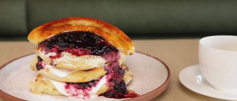 A stack of pancakes with a berry compote on a plate.