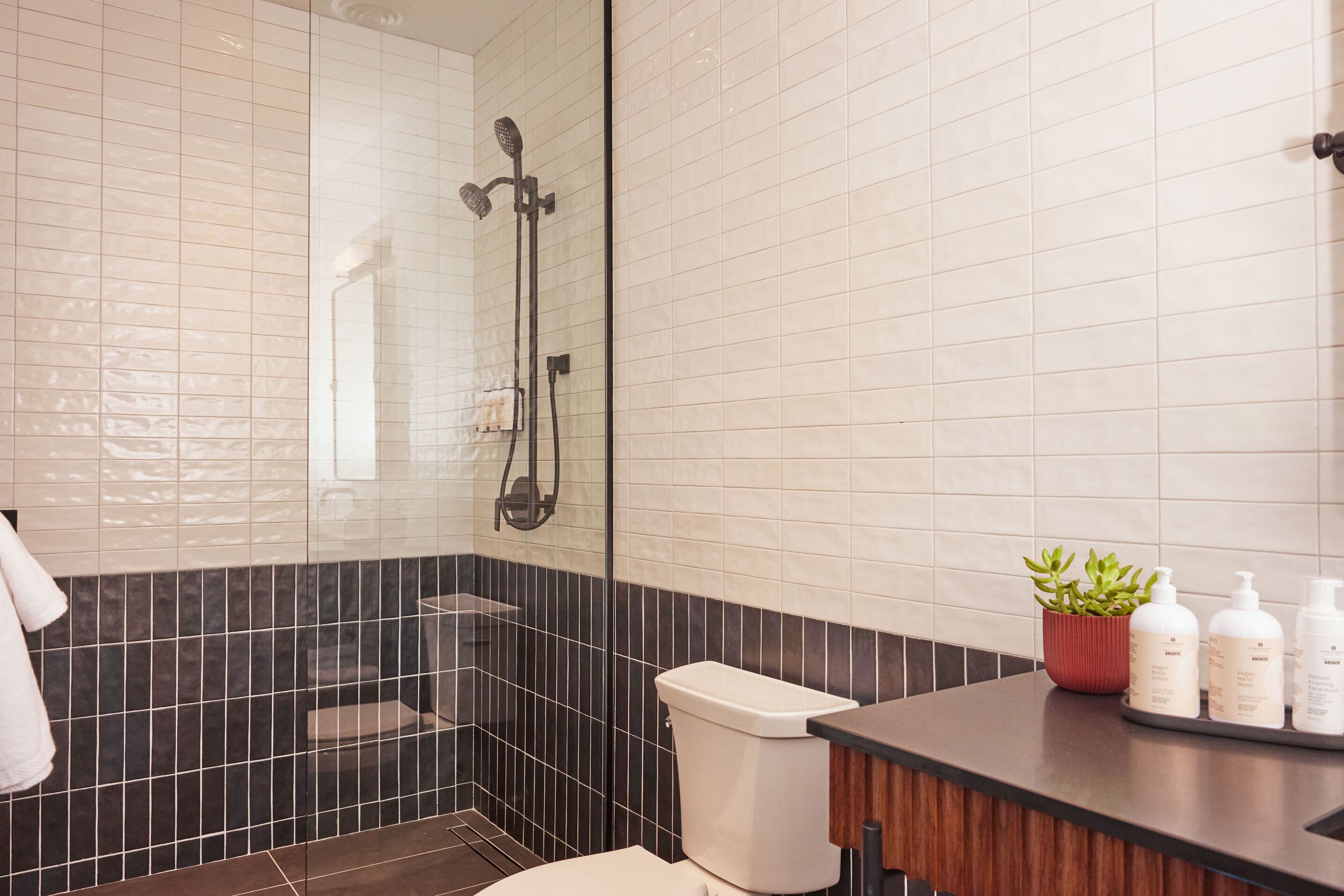 A bathroom with a shower, toilet, and a vanity with toiletries.