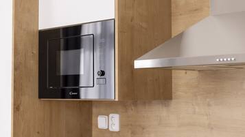 Uma cozinha moderna com micro-ondas integrado, exaustor de aço inoxidável e bancada de madeira.