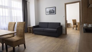 Un saló modern amb un sofà fosc, cadires de vimetes, una taula de menjador de fusta i un quadre amb marc a la paret.