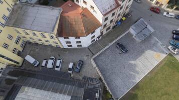 An aerial view of a city intersection with buildings, parked cars, and a cobblestone street.