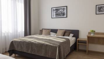 A neatly arranged bedroom with a bed, bedside table, and two framed pictures on the wall.