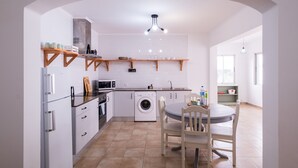 Une cuisine compacte avec des meubles blancs, un lave-linge encastré et un coin repas comprenant une table ronde et des chaises.
