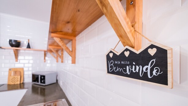Une cuisine avec des carreaux blancs, des poutres en bois et une pancarte sur laquelle on peut lire : « 10, soyez les bienvenus ».