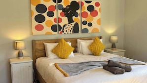 A neatly made bed with a patterned throw, wooden headboard, and two bedside lamps. - Fuss-Free Family home | Pool & Fireplace (Cape Town)