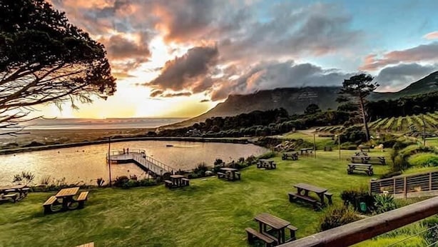 A lakeside view with picnic tables and a wooden deck overlooking the water. - Fuss-Free Family home | Pool & Fireplace (Cape Town)