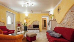 A living room with a fireplace, red sofas, a TV, and a stone wall. - Pokrajac in Rovinjsko Selo  - Haus für 4-5 Personen (Rovinj)