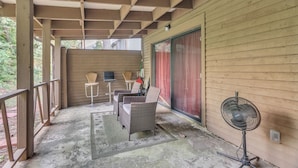 A covered patio area with wicker furniture, a standing fan, and a sliding glass door. - Centrally Located 4br Stonecrest Condo 4 Bedroom Condo by RedAwning (Lithonia)