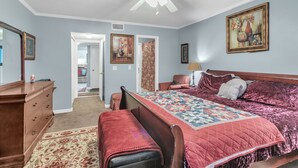 A bedroom with a wooden bed, a ceiling fan, and a door leading to a hallway. - Centrally Located 4br Stonecrest Condo 4 Bedroom Condo by RedAwning (Lithonia)