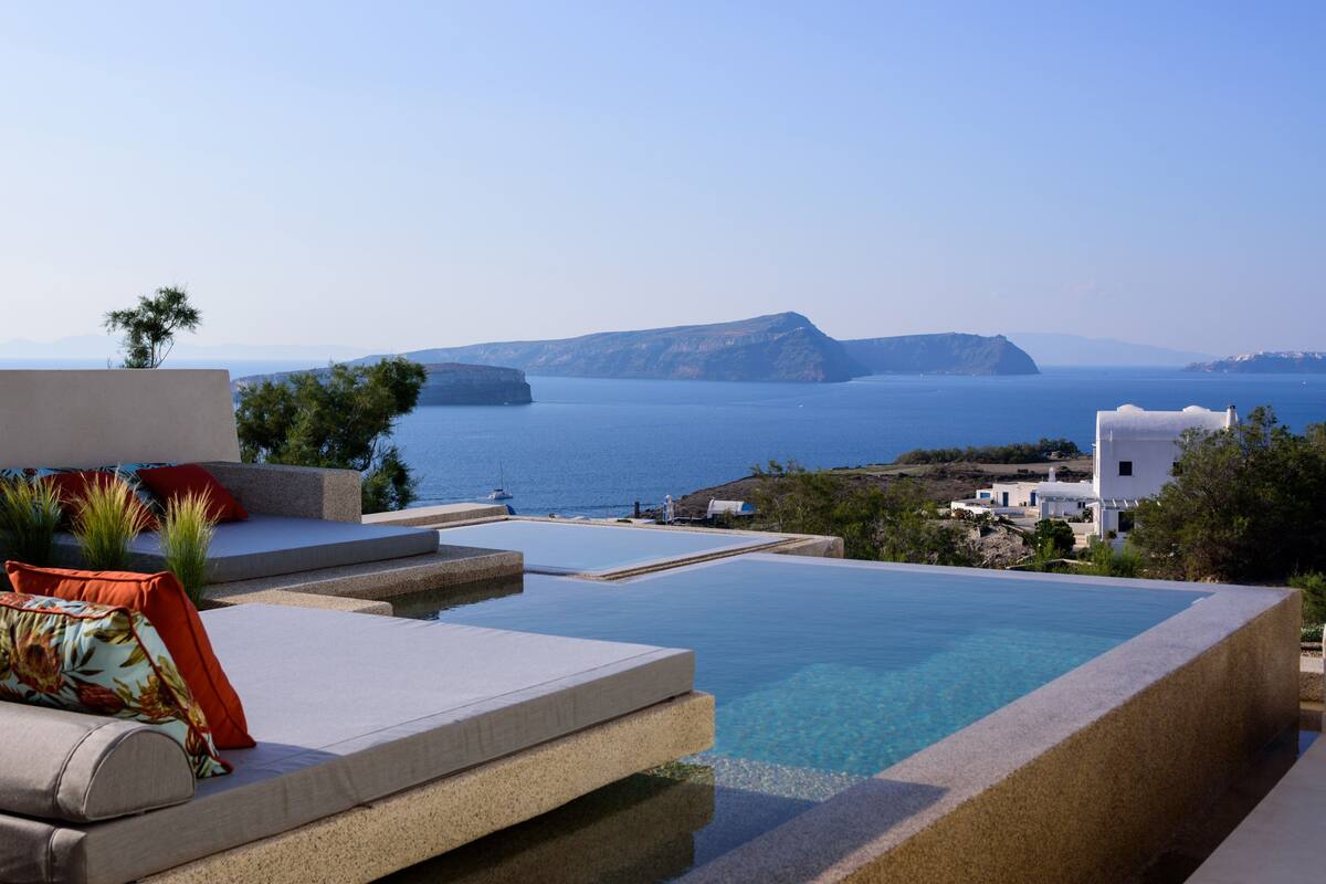 A pool area with a view of the sea and distant mountains.