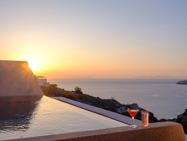 A sunset view from a balcony with a drink on the edge.