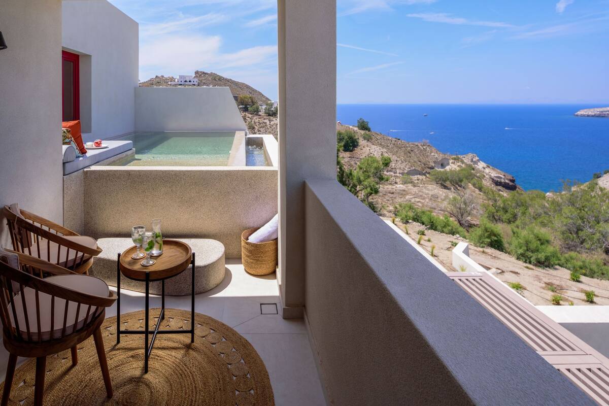 A balcony with a pool, chairs, and a table.