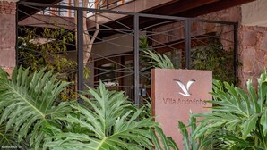 Un cartel de Villa Andorinha con una estructura arquitectónica moderna al fondo.