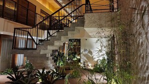 Un interior moderno con una escalera, techo de madera y plantas de interior.