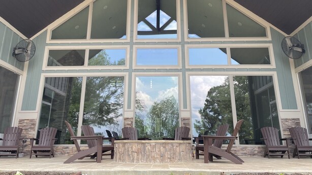 Une vaste terrasse ouverte, dotée de fauteuils Adirondack et d’une cheminée en pierre.