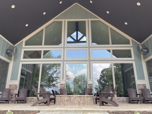 A large, open patio with Adirondack chairs and a stone fireplace. - Cypress Cove Pointe *Waterfront with Dock* (Milam)