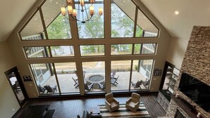 Un salon spacieux avec un grand canapé d’angle, une cheminée et une vue sur une terrasse extérieure, accessible par de grandes fenêtres.