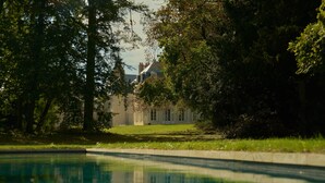 A swimming pool surrounded by lush greenery and a large building in the background. - Exquisite Château de Thauvenay surrounded by Sancerre vineyards, 24 beds 23bath  (Thauvenay)