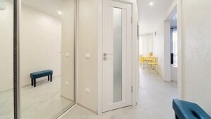 A hallway with a bench, a door with frosted glass, and a dining area with yellow chairs and a table. - Apartment on Nemiga (Minsk)
