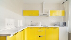 A modern kitchen with white and yellow cabinetry, a microwave, and a sink. - Apartment on Nemiga (Minsk)