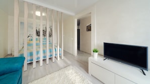 A modern living room with a sofa, a flat-screen TV, a white cabinet, and a decorative wall panel. - Apartment on Nemiga (Minsk)