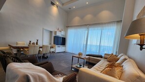 A modern living room with a sofa, armchairs, a coffee table, and a TV. - Condominio Aquamarina (Punta Cana)