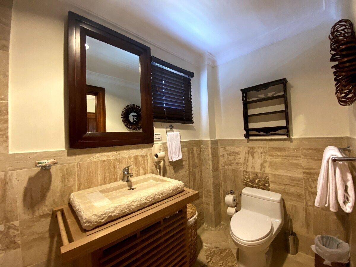 Une salle de bain avec un meuble-lavabo en bois, un miroir, des toilettes et un porte-serviettes.